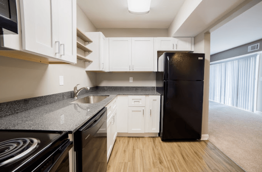 an empty kitchen with black appliances and white cabinets