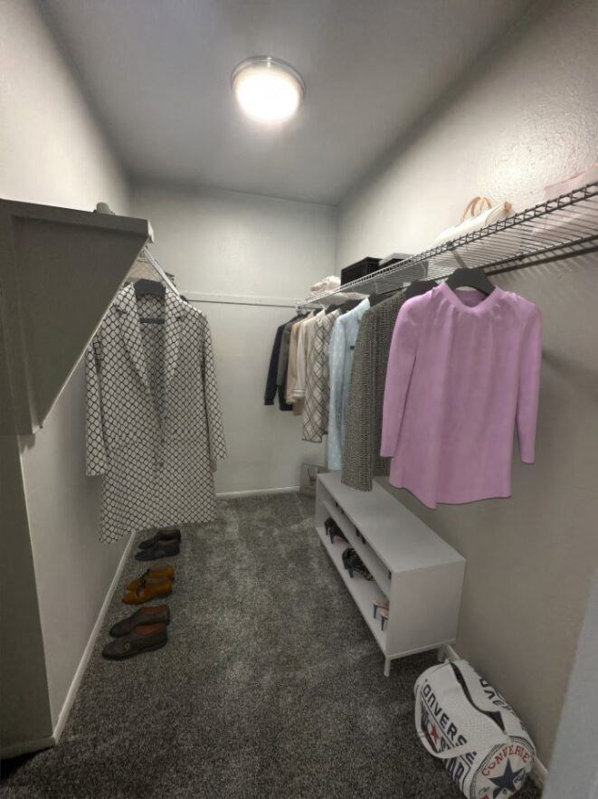 a walk in closet with a white dresser and clothes hanging on the wall