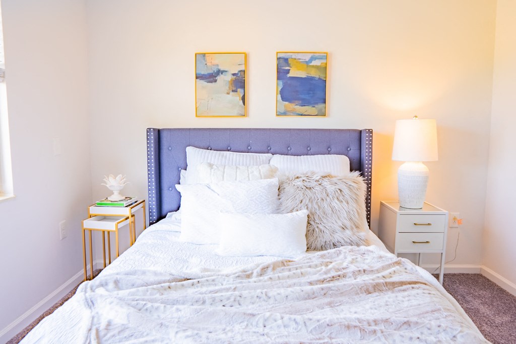 a bedroom with a bed with white sheets and pillows and two nightstands