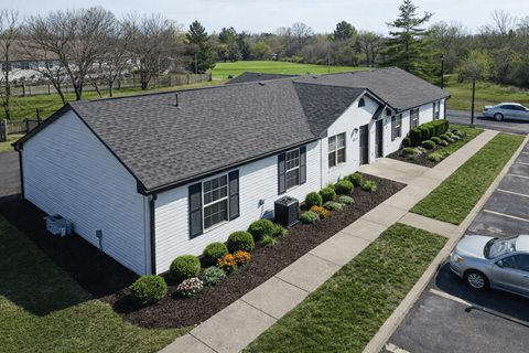 A white building with a black roof and a parking lot in front.