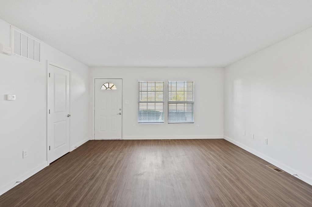 an empty living room with white walls and wood flooring