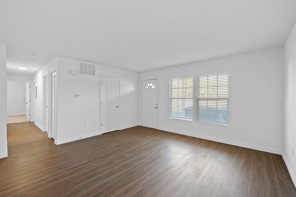 an empty living room with wood floors and white walls