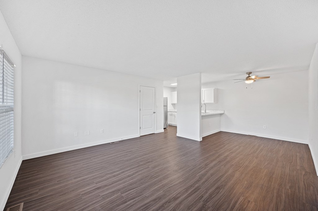 the living room of an apartment with wood flooring and a ceiling fan