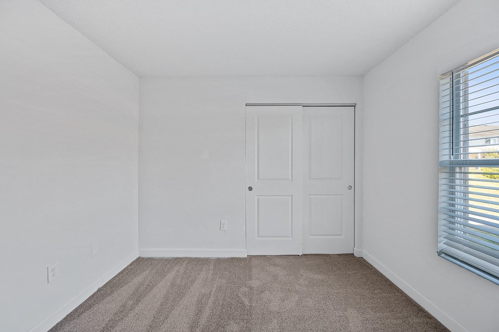 an empty bedroom with white walls and a door and window