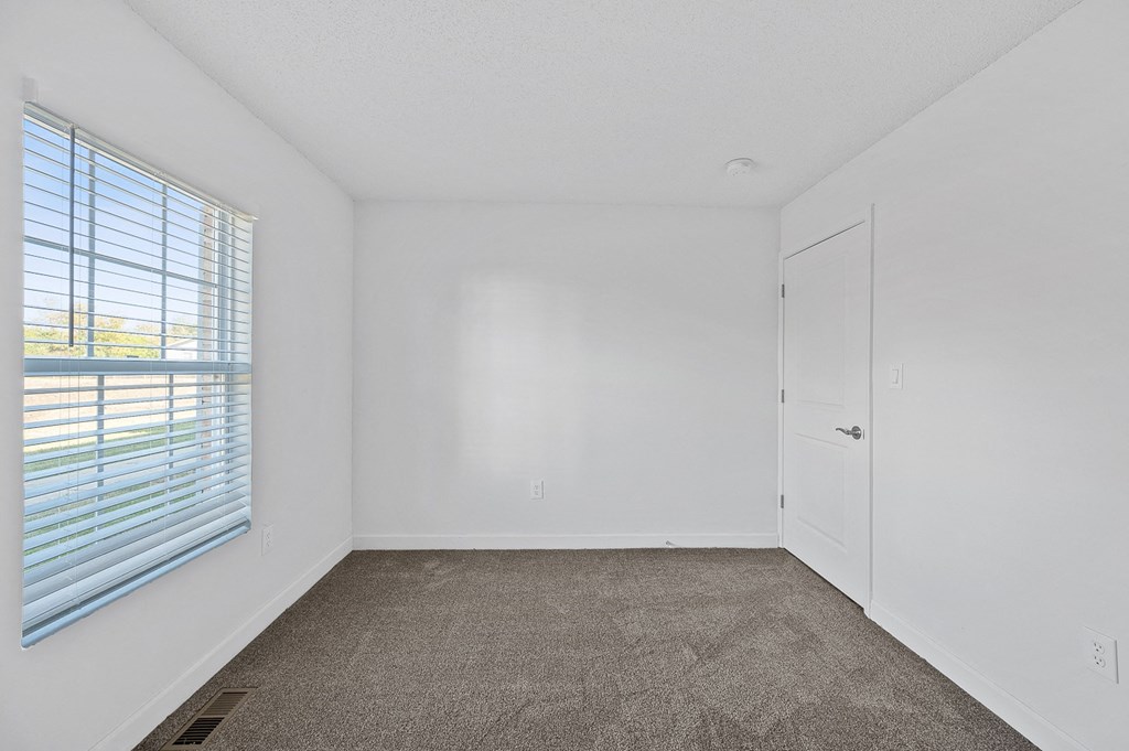 an empty bedroom with a large window and white walls