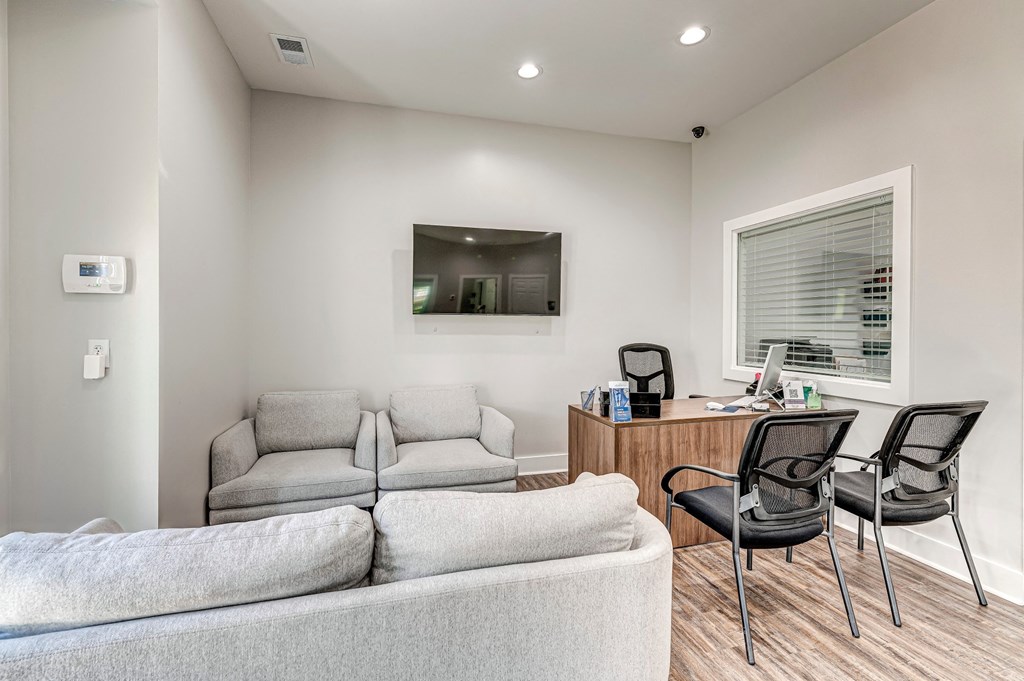 A modern living room with a grey couch, a white chair, and a wooden desk. at The Apex, Cincinnati