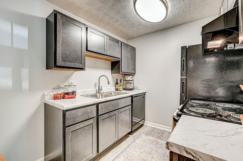 A kitchen with a black stove top oven and a white sink.