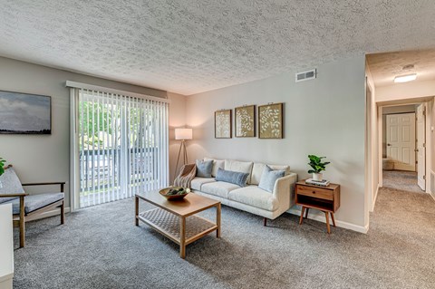 A living room with a couch, a chair, a coffee table, and a painting on the wall.