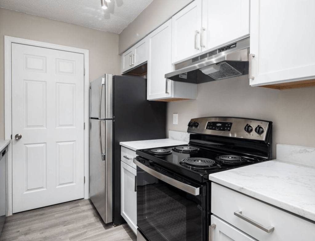 a kitchen with white cabinets and black appliances and a refrigerator at The Berryessa Apartments, Columbus, Ohio