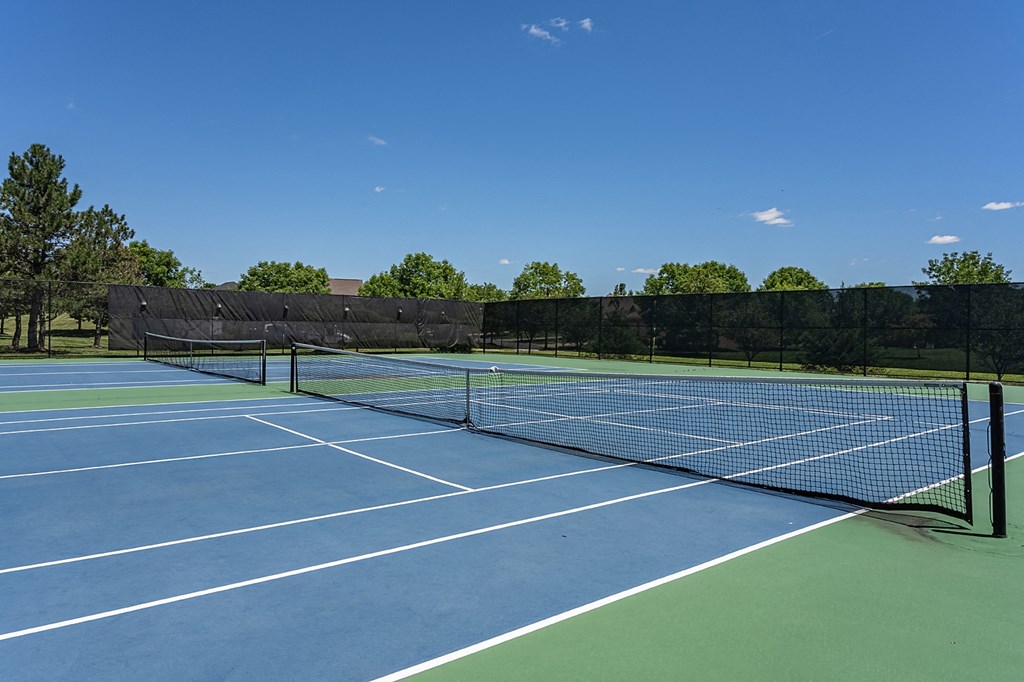 a tennis court on a sunny day with trees in the background at Bishops Gate, Ohio