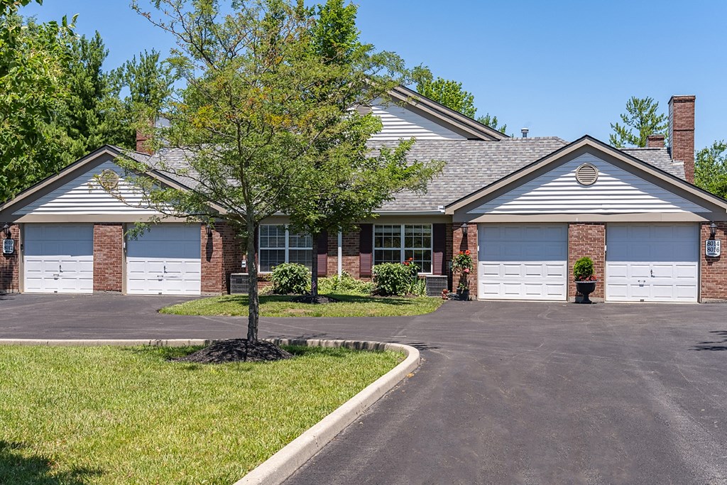 a house with two garage doors and a tree in front of it