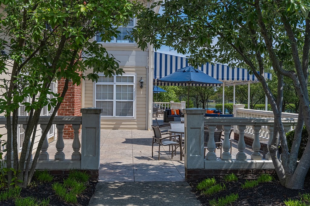 a patio with tables and chairs and a blue umbrella in front of a building at Bishops Gate, Cincinnati, OH