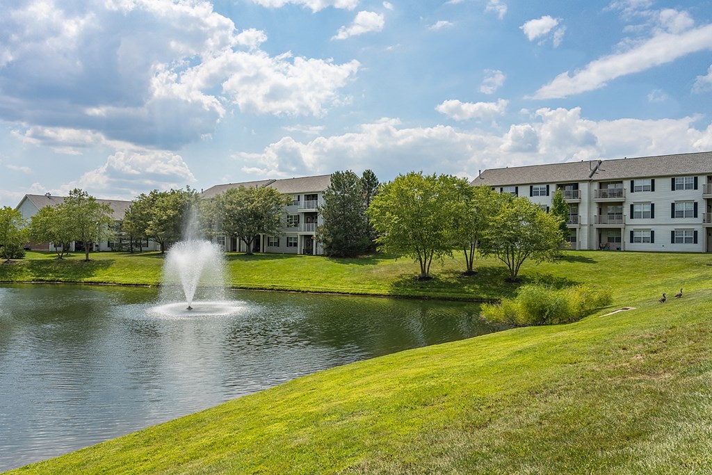 a fountain in the pond with an apartment building in the background at Bishops Gate, Ohio