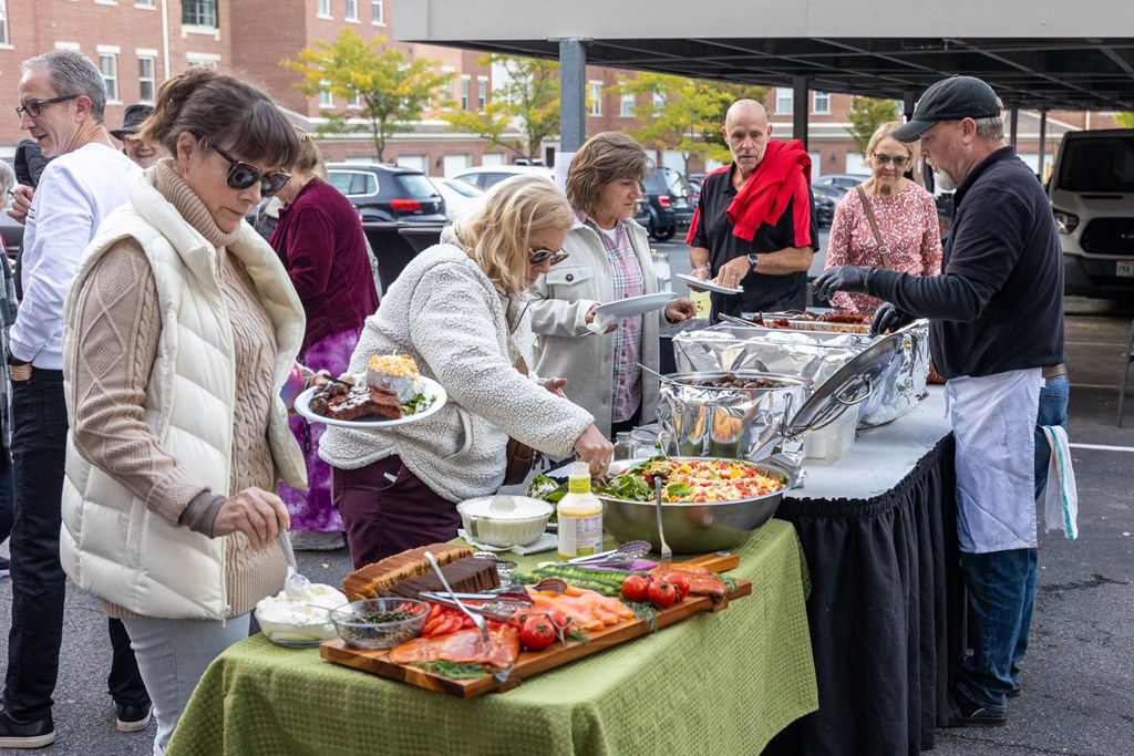 people line up to get food from a buffet table