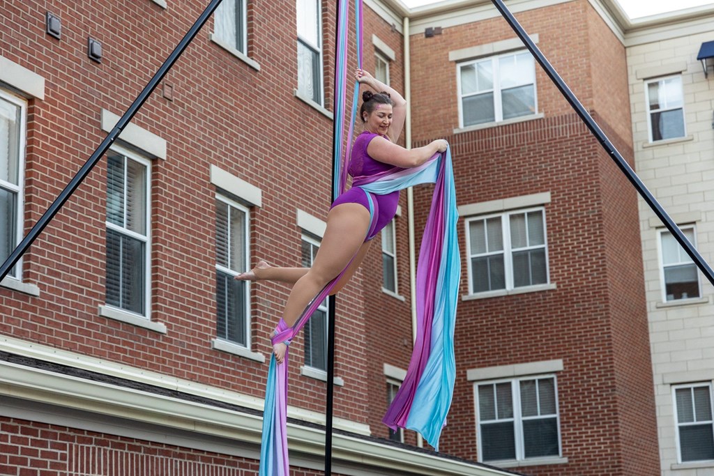 a woman hanging from a pole in front of a brick building