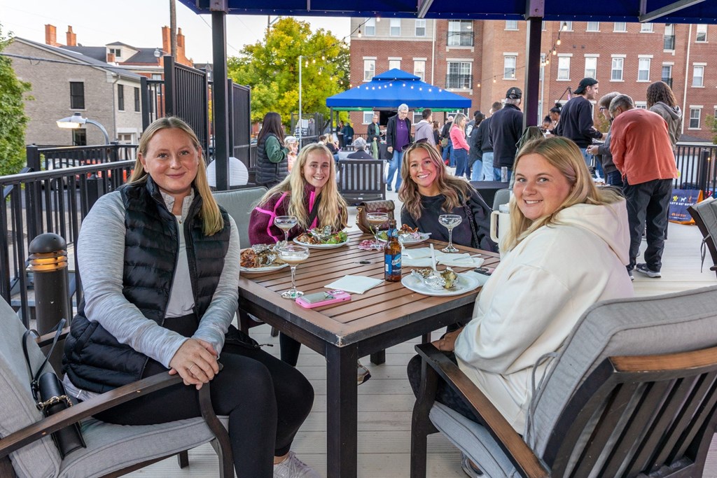 a group of women sitting at a patio table eating food