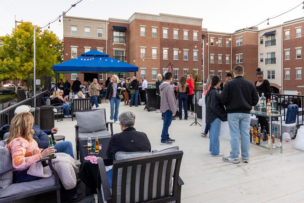 a crowd of people standing and sitting around an outdoor patio