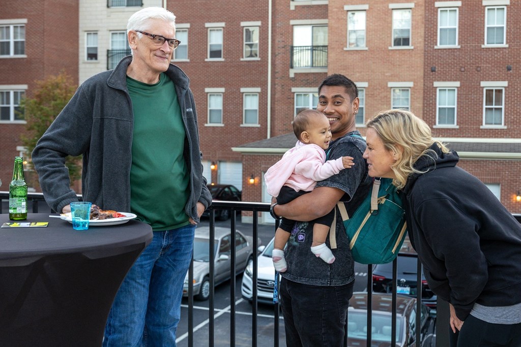 people standing on a balcony holding a baby and a woman holding a child
