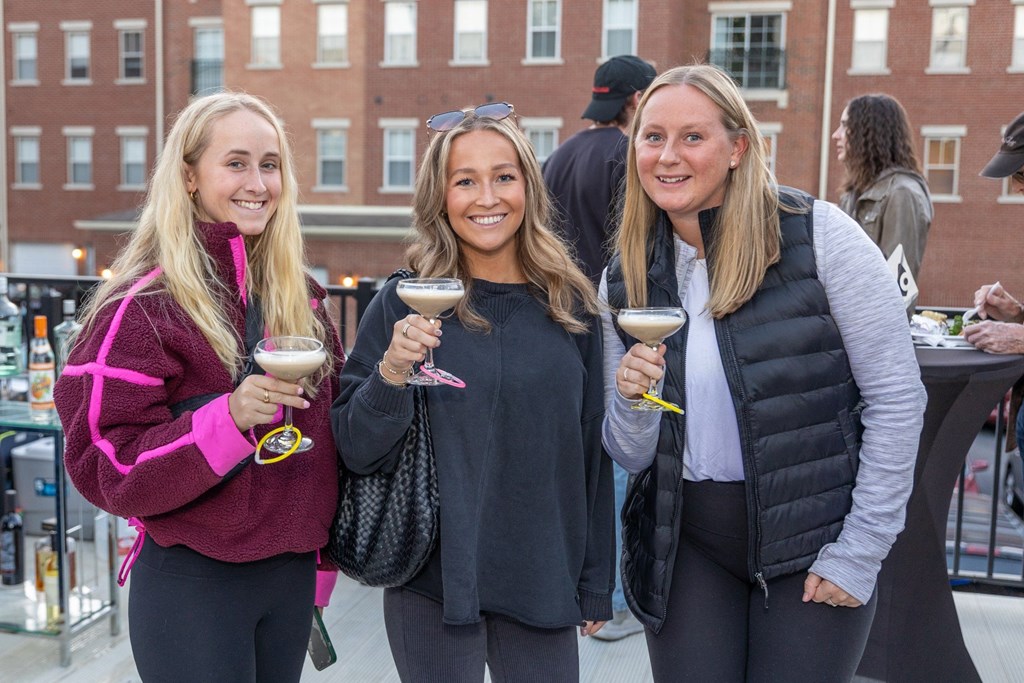 three women holding wine glasses and posing for a picture