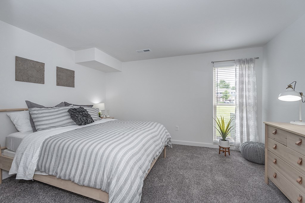 Bedroom with cozy bed and window at Bloomfield Apartments, Dayton