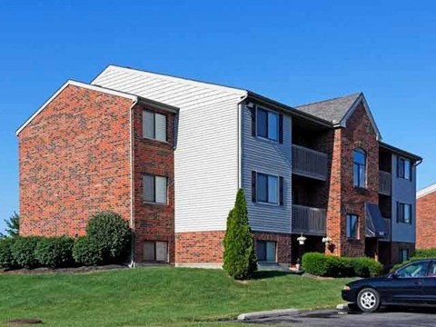 A black car is parked in front of a two-story apartment building.