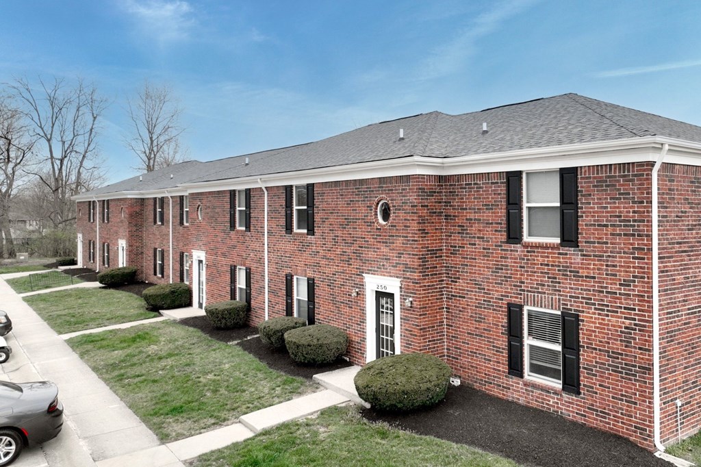 A red brick building with black shutters and a grey roof.