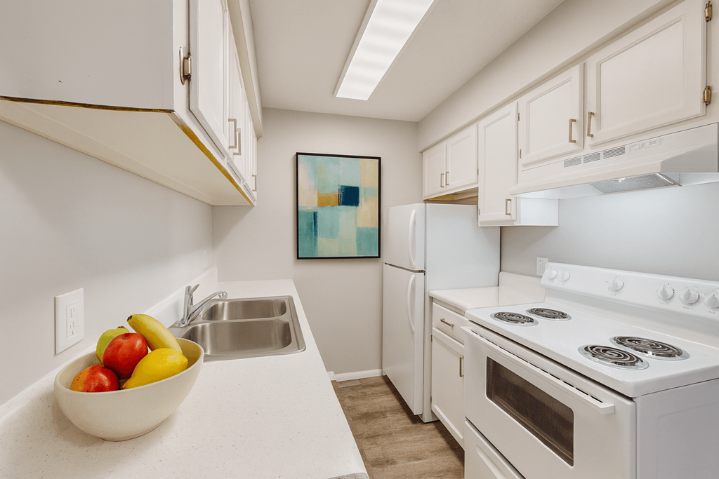A kitchen with a white stove and a bowl of fruit on the counter.