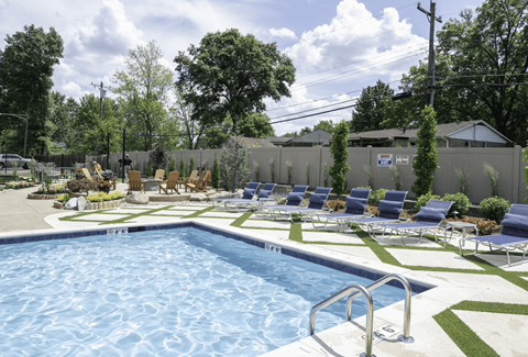 a swimming pool with chaise lounge chairs and a grassy area with trees in the background at Olde Towne in Kenwood, Ohio, 45243