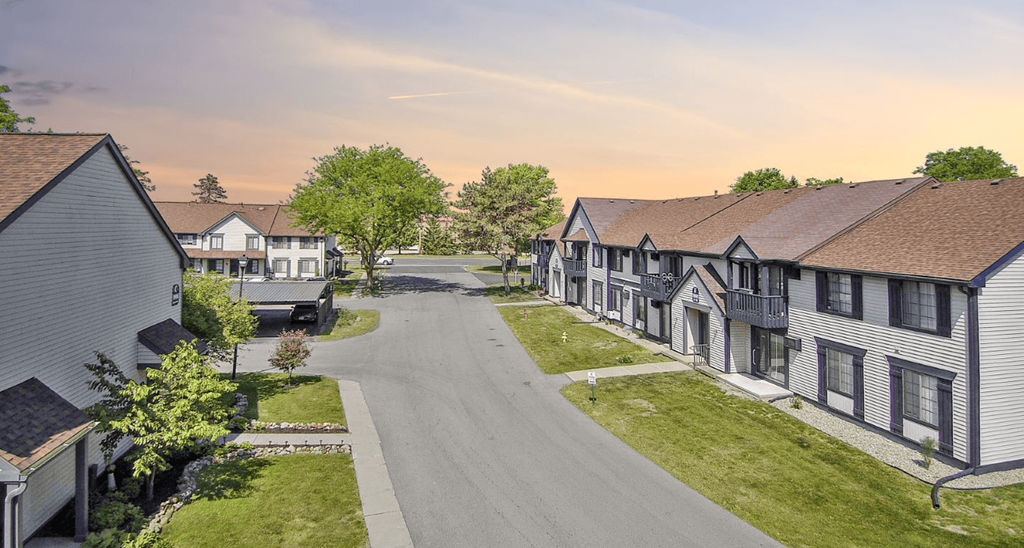 a row of houses on a street with a sunset in the background