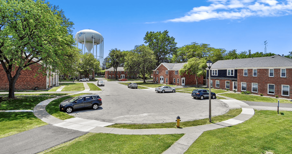 a parking lot in front of a brick building with a water tower in the background