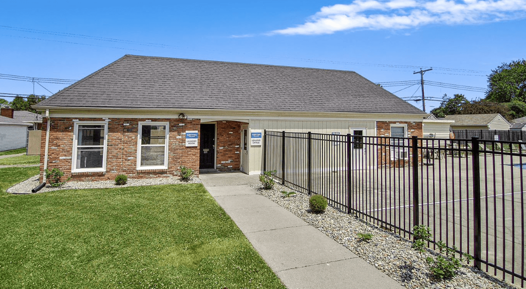 a small brick building with a black fence in front of it