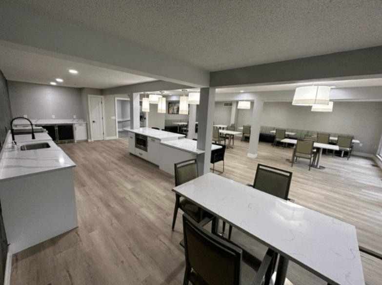 a large room with tables and chairs and a kitchen