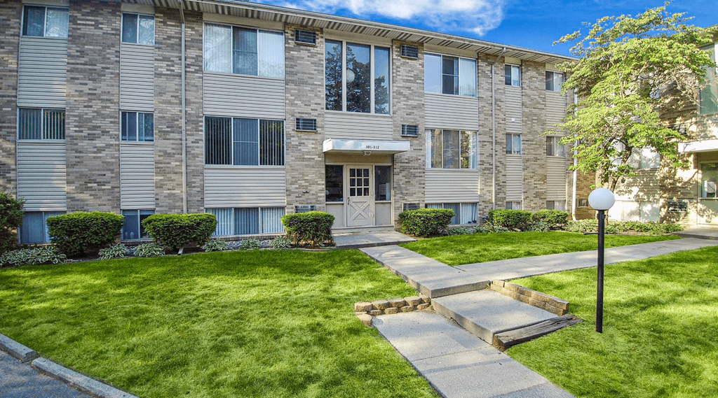 an apartment building with a lawn and walkway in front of it
