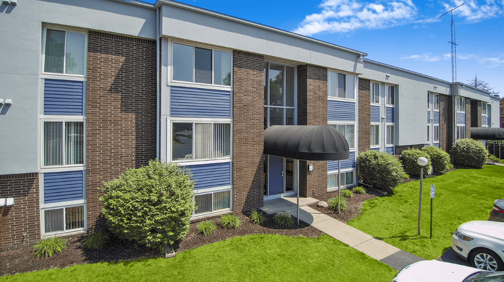a brick apartment building with blue shutters and a green lawn