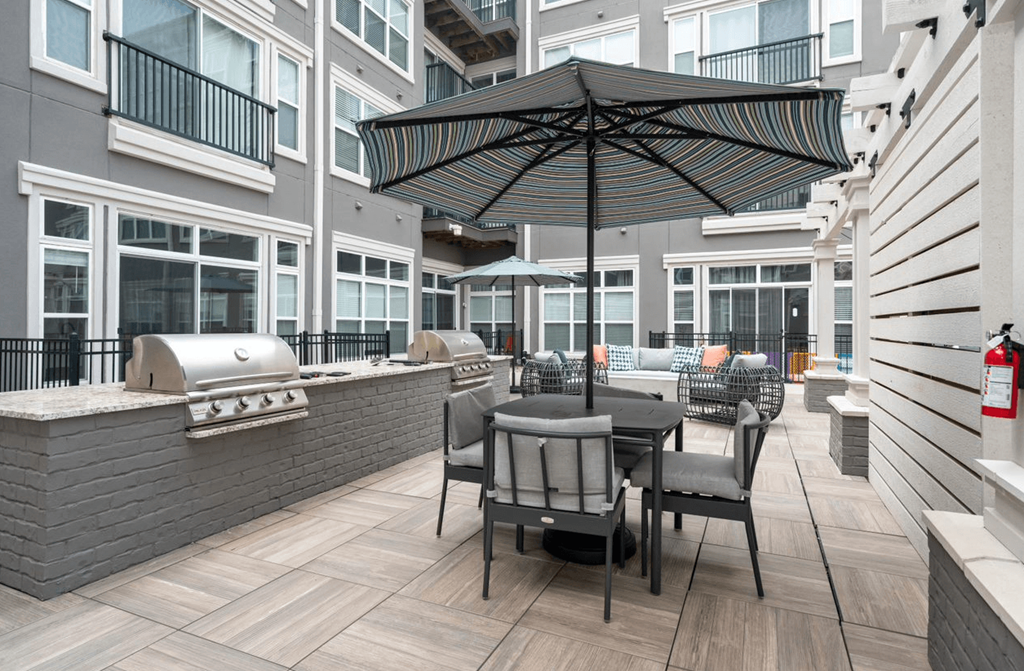 a patio with a grill and umbrella at the bradley braddock road station apartments
