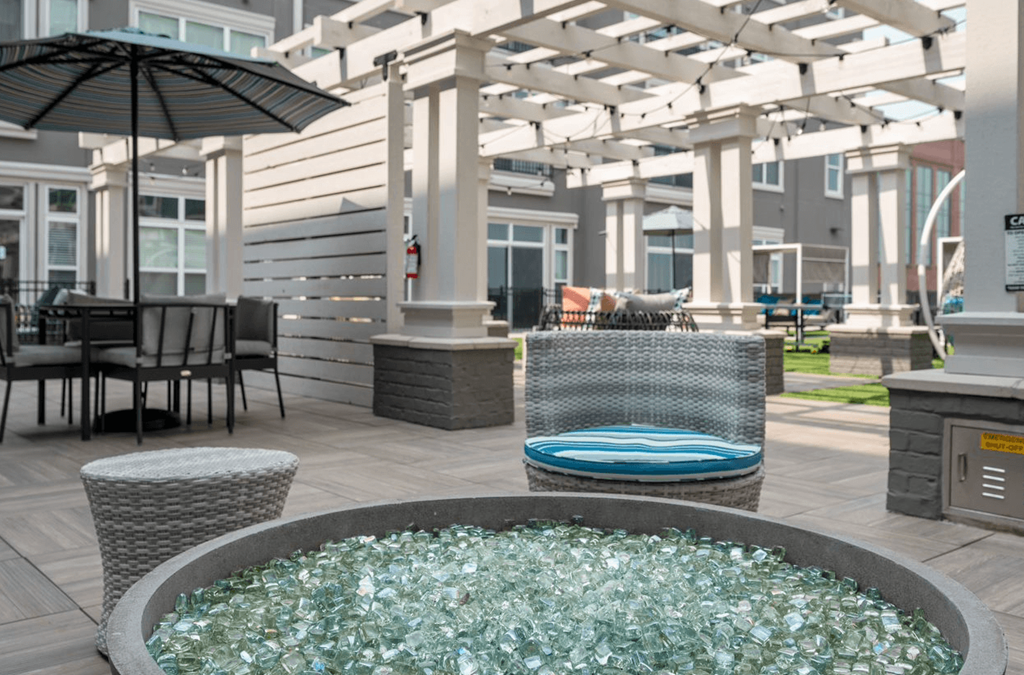 a patio with a jacuzzi and tables with chairs and umbrellas