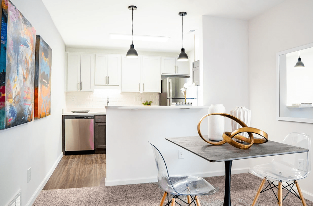 a dining area with a table and chairs and a kitchen in the background