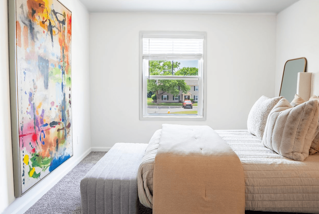 a bedroom with a large painting on the wall and a bed with a blanket and pillows