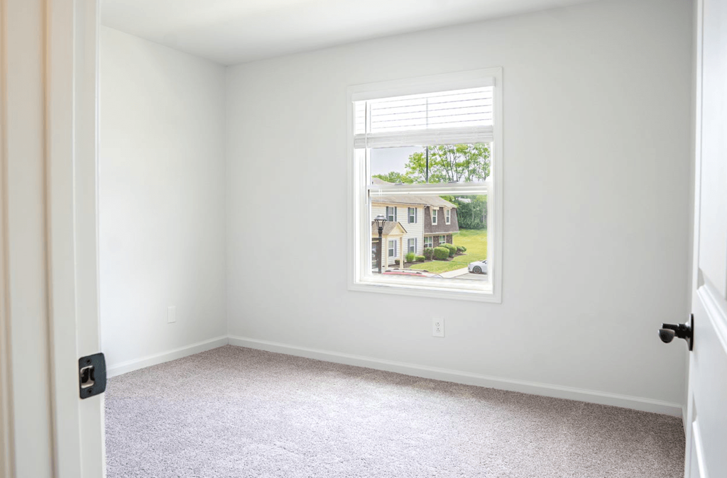 a bedroom with a large window and a carpeted floor