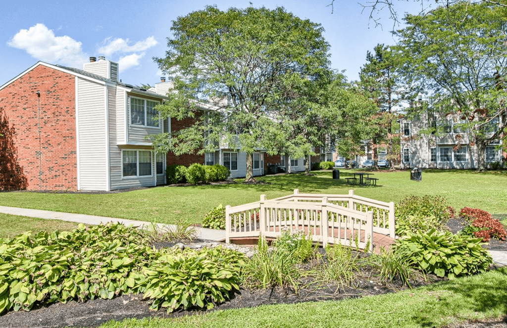 a small wooden bridge crosses a grassy area in front of a brick building at The Berryessa Apartments, Ohio, 98104