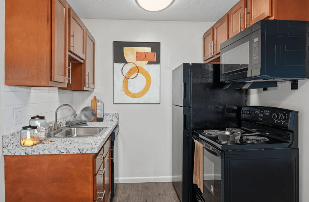 a kitchen with a black stove top oven next to a sink and a refrigerator at The Woodridge Collection, Ohio