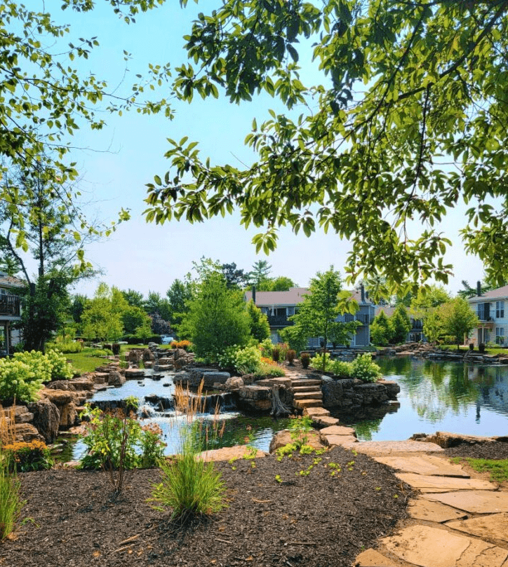 a pond with rocks and trees in the background at Harpers Point Apartments, Cincinnati, OH