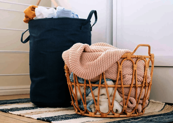 a basket of clothes next to a black bag