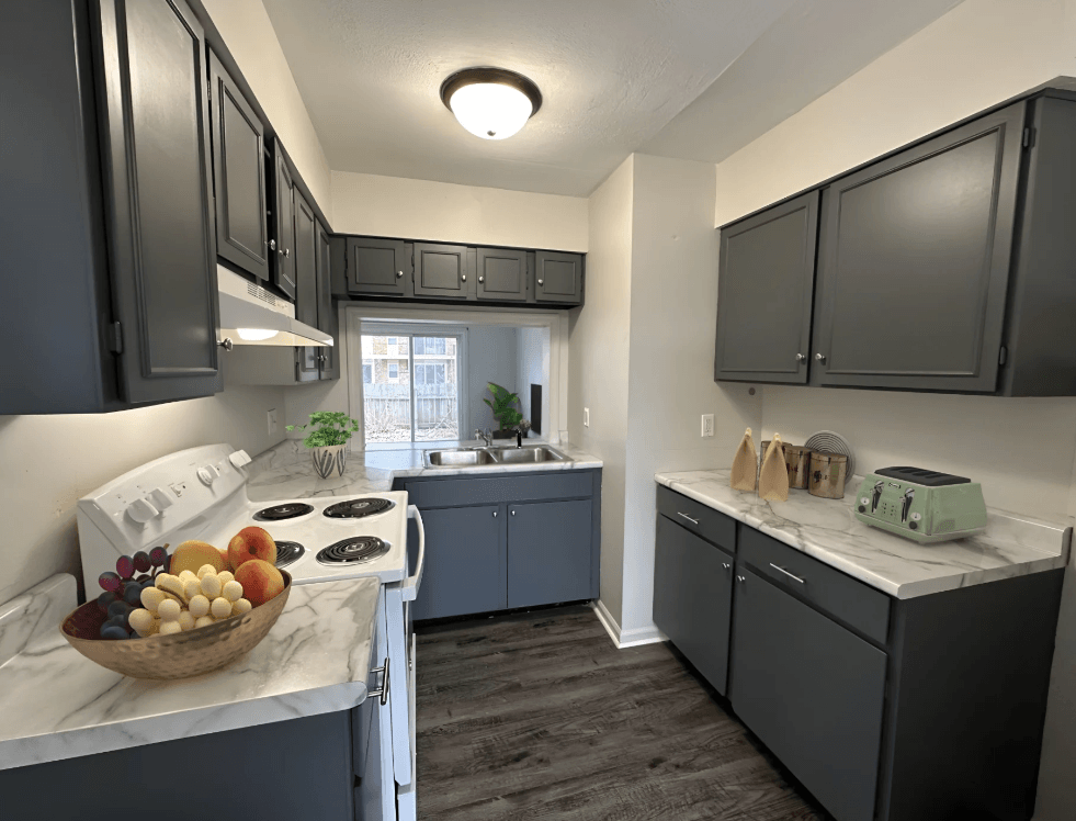 a kitchen with gray cabinets and a bowl of fruit on the counter