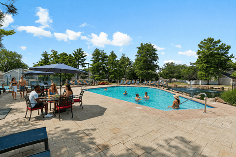 A group of people are sitting at a table by a pool.
