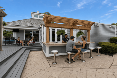A group of people are sitting at a bar on a patio.