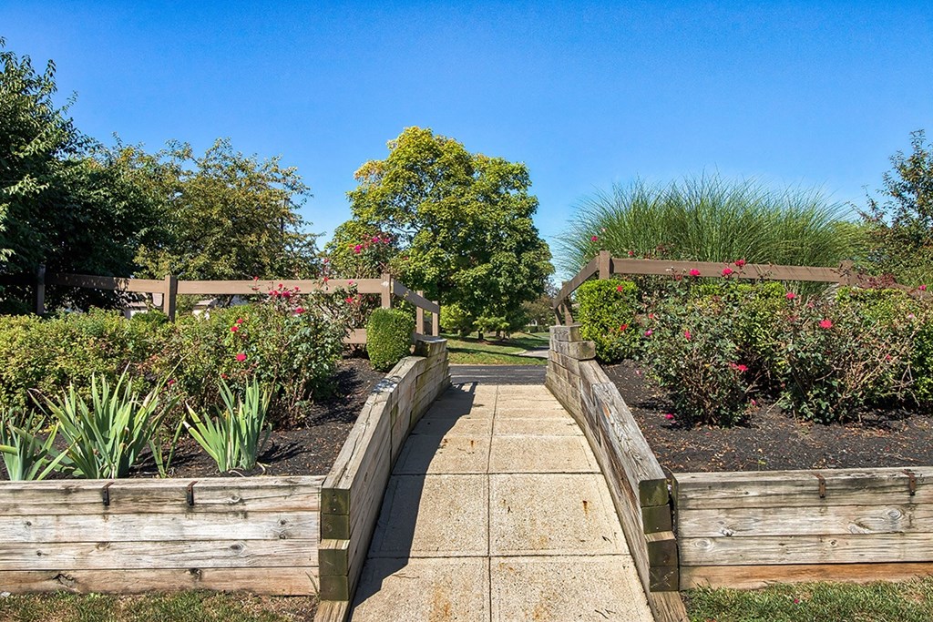 A wooden bridge leads to a lush garden.