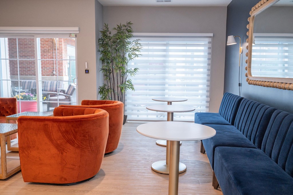 a living room with couches tables and chairs and a mirror at Monmouth Row Apartments, Newport, KY