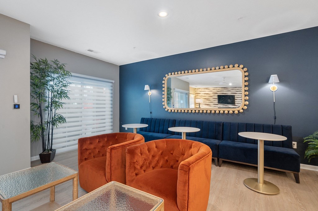 a living room with blue walls and orange chairs and a mirror at Monmouth Row Apartments, Newport, Kentucky