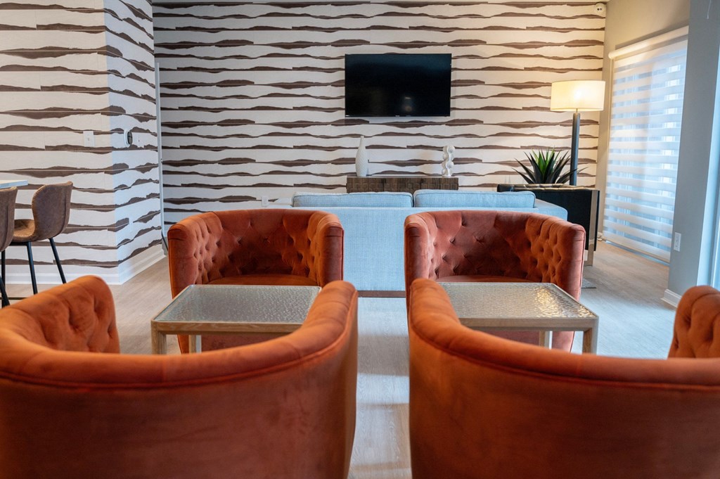 a seating area with orange chairs and a television at Monmouth Row Apartments, Newport, KY